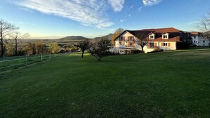 A large house with a spacious lawn and a clear view of the surrounding landscape. - Hotel Les Bergeronnettes (Champagneux)
