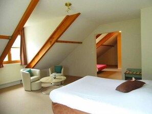 A bedroom with a bed, a chair, a small table, and a window. - Hotel Les Bergeronnettes (Champagneux)