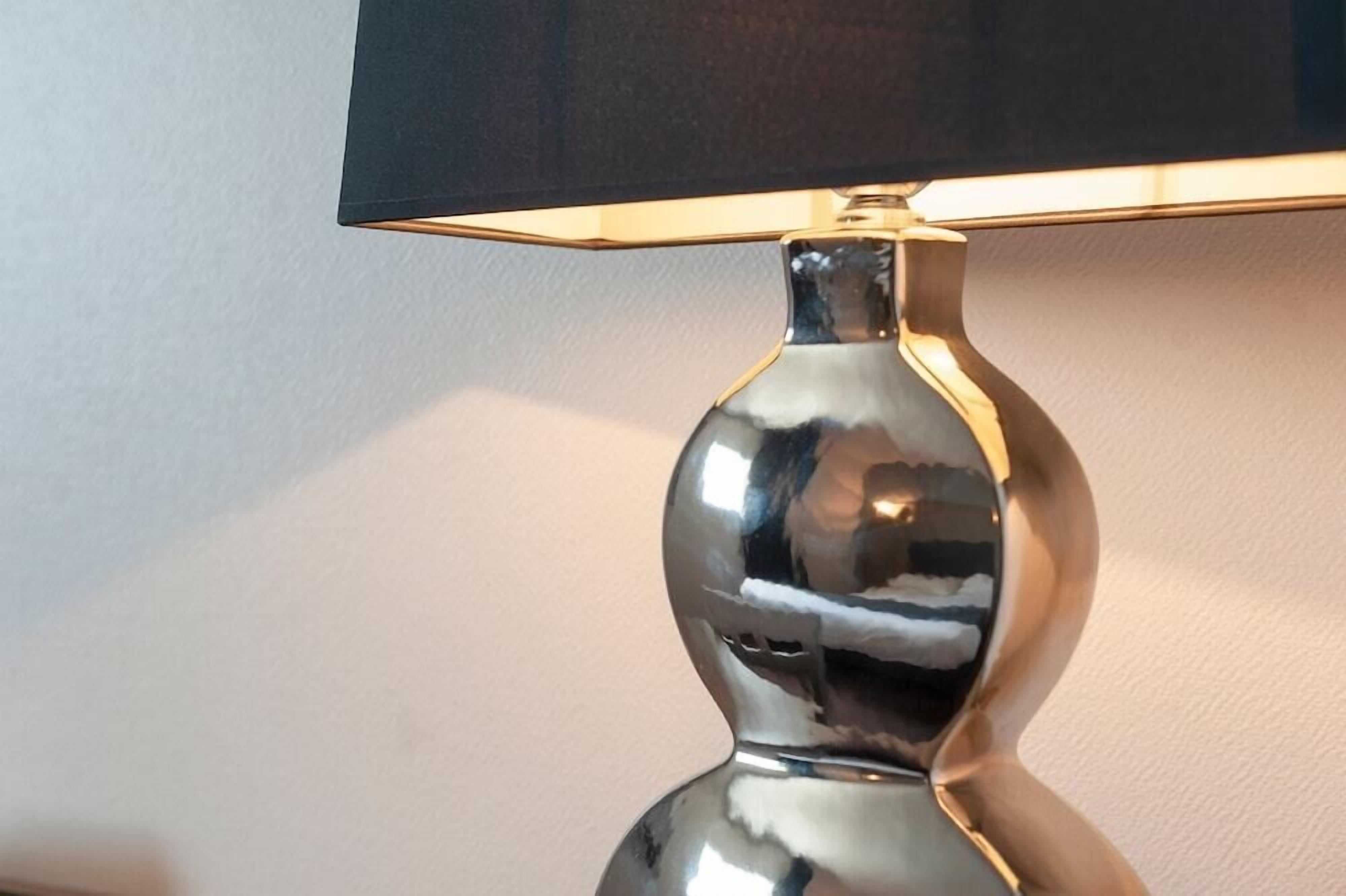 Een metalen lamp met een reflecterend oppervlak en een zwarte kap.