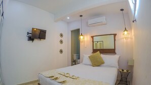 Ein Hotelzimmer mit einem Bett, einem Fernseher, einer Klimaanlage und einem kleinen Tisch mit einer Lampe.