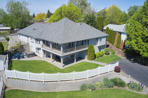A two-story house with a balcony, a stone retaining wall, and a white picket fence.