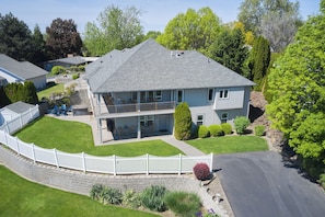 A two-story house with a front porch, a covered patio, and a stone retaining wall.