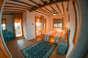 A cozy bedroom with a bed, a small table, a chair, and a window.