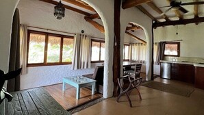 A spacious living area with a wooden table and chairs, a kitchen area, and large windows allowing natural light. - Ensueno Holbox & Beach Club (Isla Holbox)