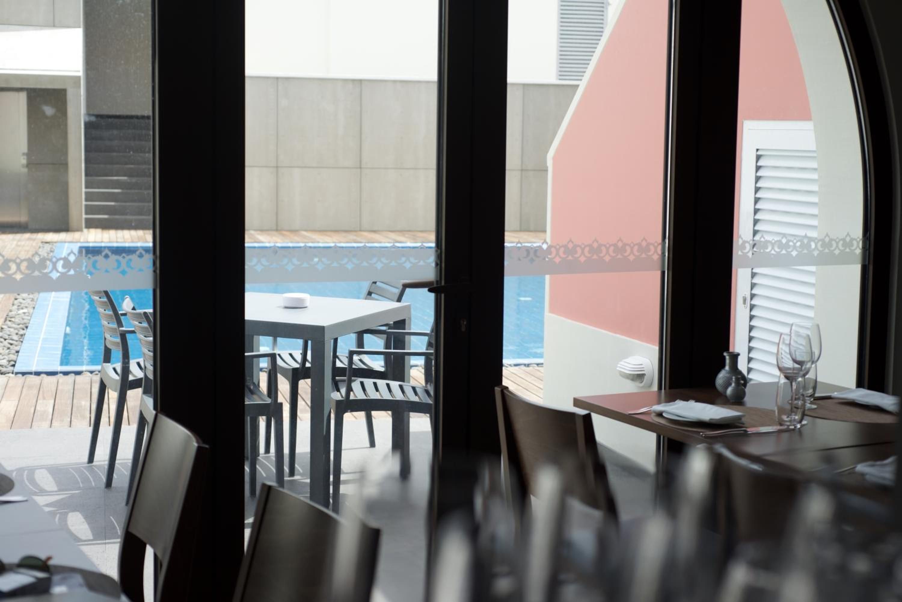 A dining area with a view of a pool and a patio.