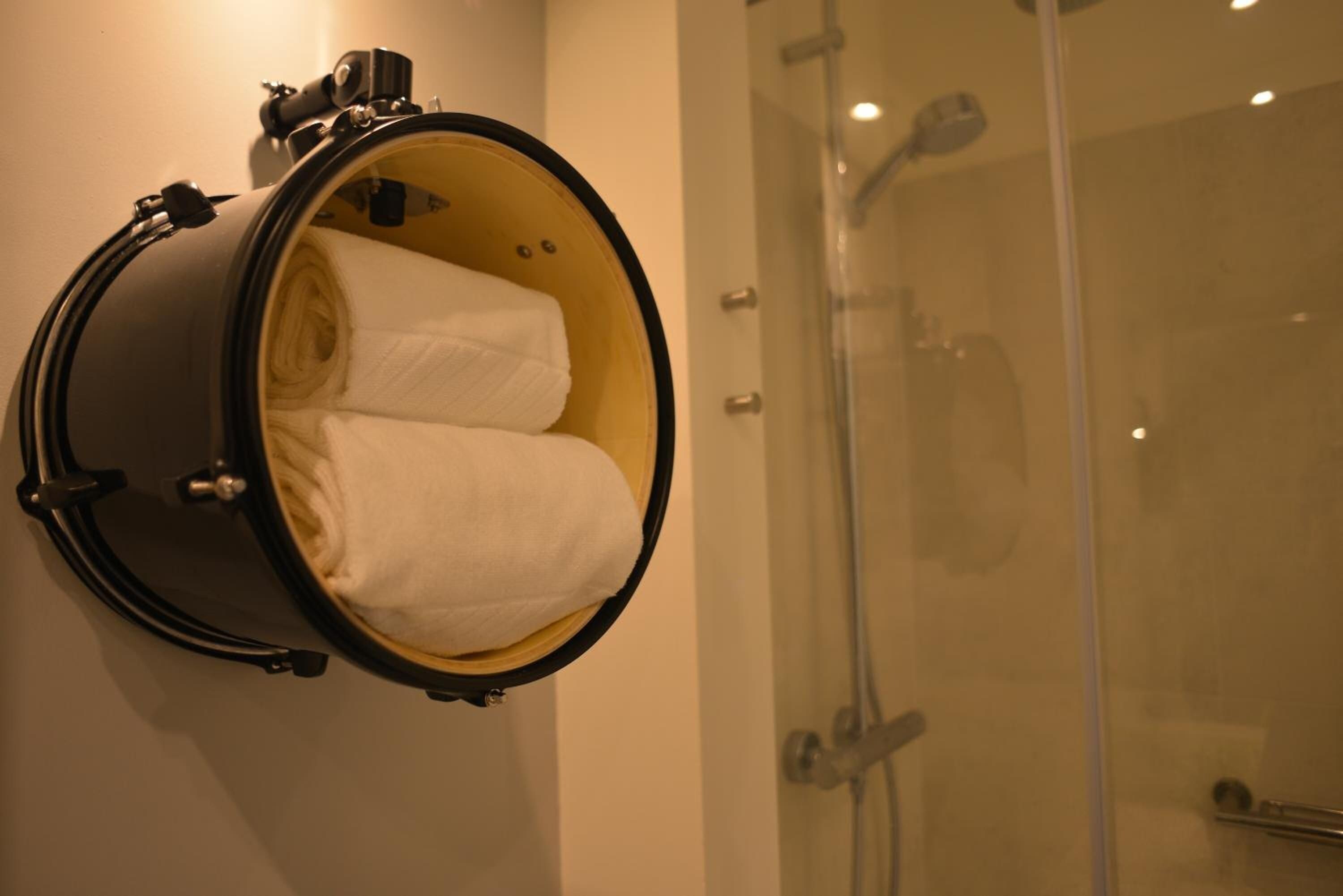 A compact, cylindrical, wall-mounted, heated towel warmer with two folded towels inside.