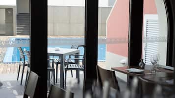 A dining area with a view of a pool and a patio.