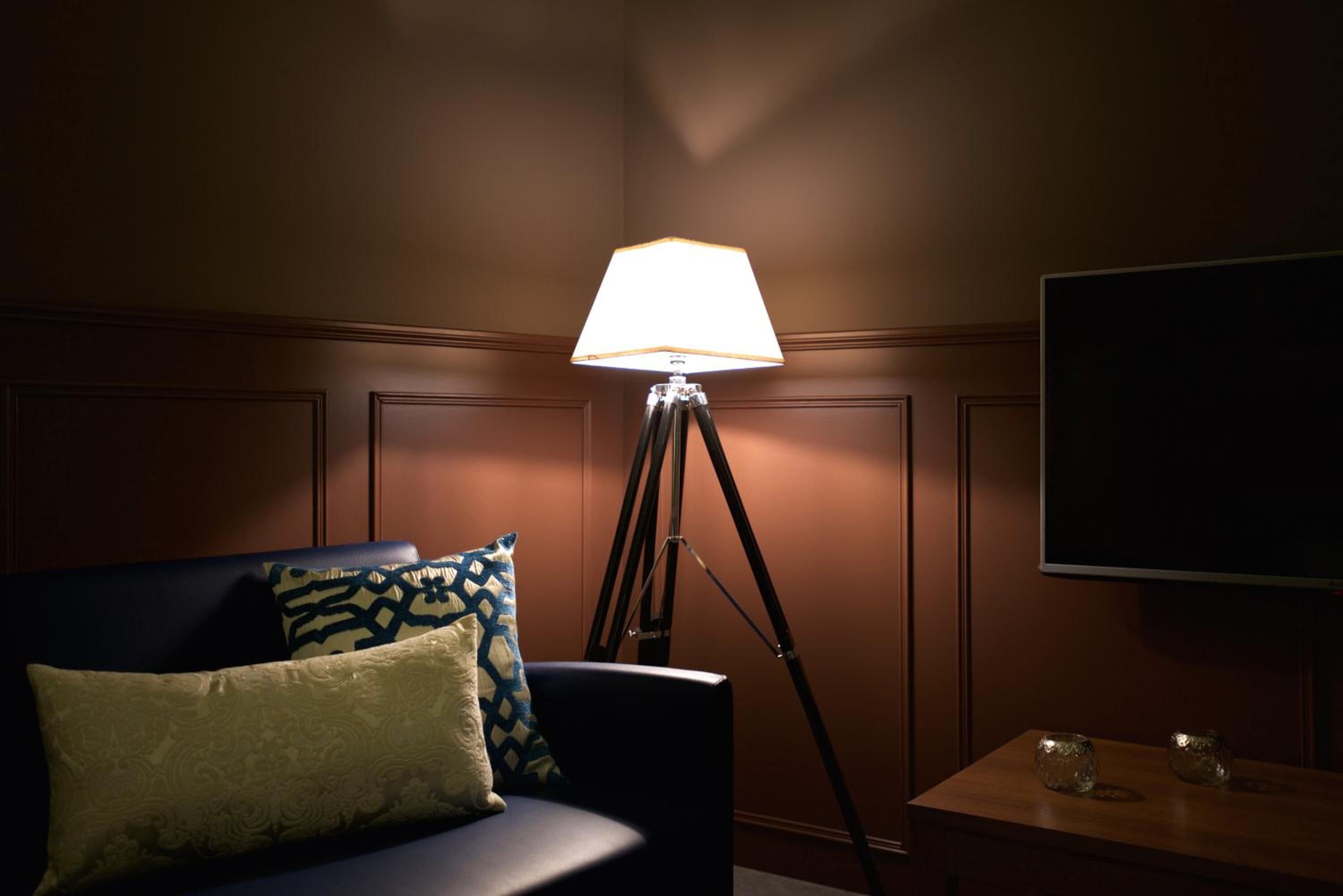 A room with a sofa, a lamp, a small table, and a television.