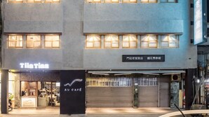 A multi-story hotel with illuminated windows and a sign for "Theia" at the ground level. - Tiintinn Inn Showtime (Taitung)