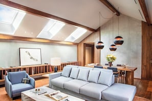 Una sala moderna con sofá, sillón y mesa de comedor.