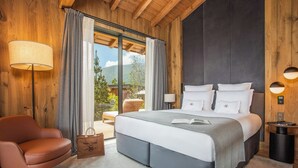 Un dormitorio con una cama grande, una silla, una mesita de noche y vistas al exterior.