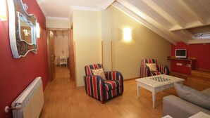 A cozy living room with striped armchairs, a coffee table, and a television on a stand. - El Corcal de Liebana (Cillorigo de Liebana)