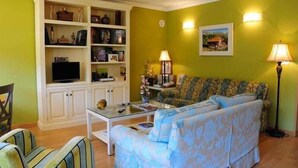A living room with a sofa, a television, a bookshelf, and a lamp. - El Corcal de Liebana (Cillorigo de Liebana)
