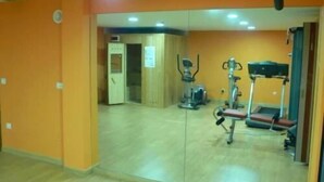 A gym with exercise equipment, a wooden cabinet, and a door leading to another room. - El Corcal de Liebana (Cillorigo de Liebana)