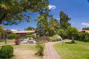 A well-maintained garden with a paved pathway leading to a building with a tiled roof.