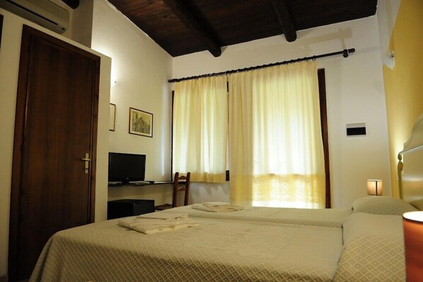 A hotel room with two beds, a desk with a computer, a chair, and a TV.