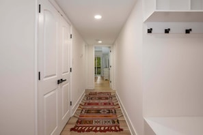 A hallway with white doors, a patterned carpet, and a white shelf. - Mount Olive Lodge | Luxury in the trees! (Basye)