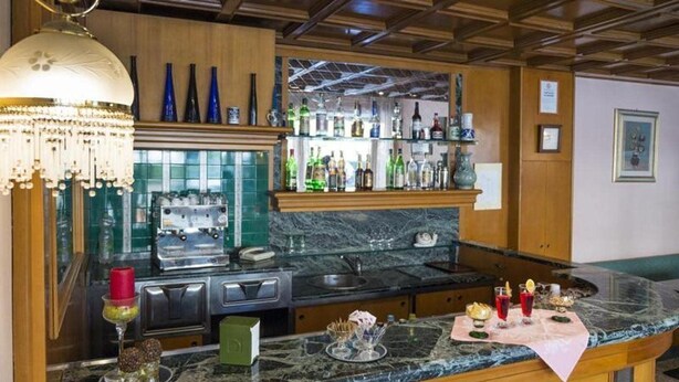 Zona de bar con encimera de mármol, candelabro y diferentes botellas y vasos.