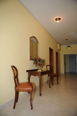 Un pasillo con una mesa de comedor, sillas, un espejo y un jarrón decorativo.