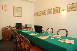 A conference room with a green table, laptops, documents, and chairs. - Grifone Hotel Ristorante (Perugia)