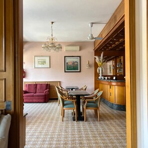 Un comedor con una mesa y sillas, una araña y una zona de bar con estantes.