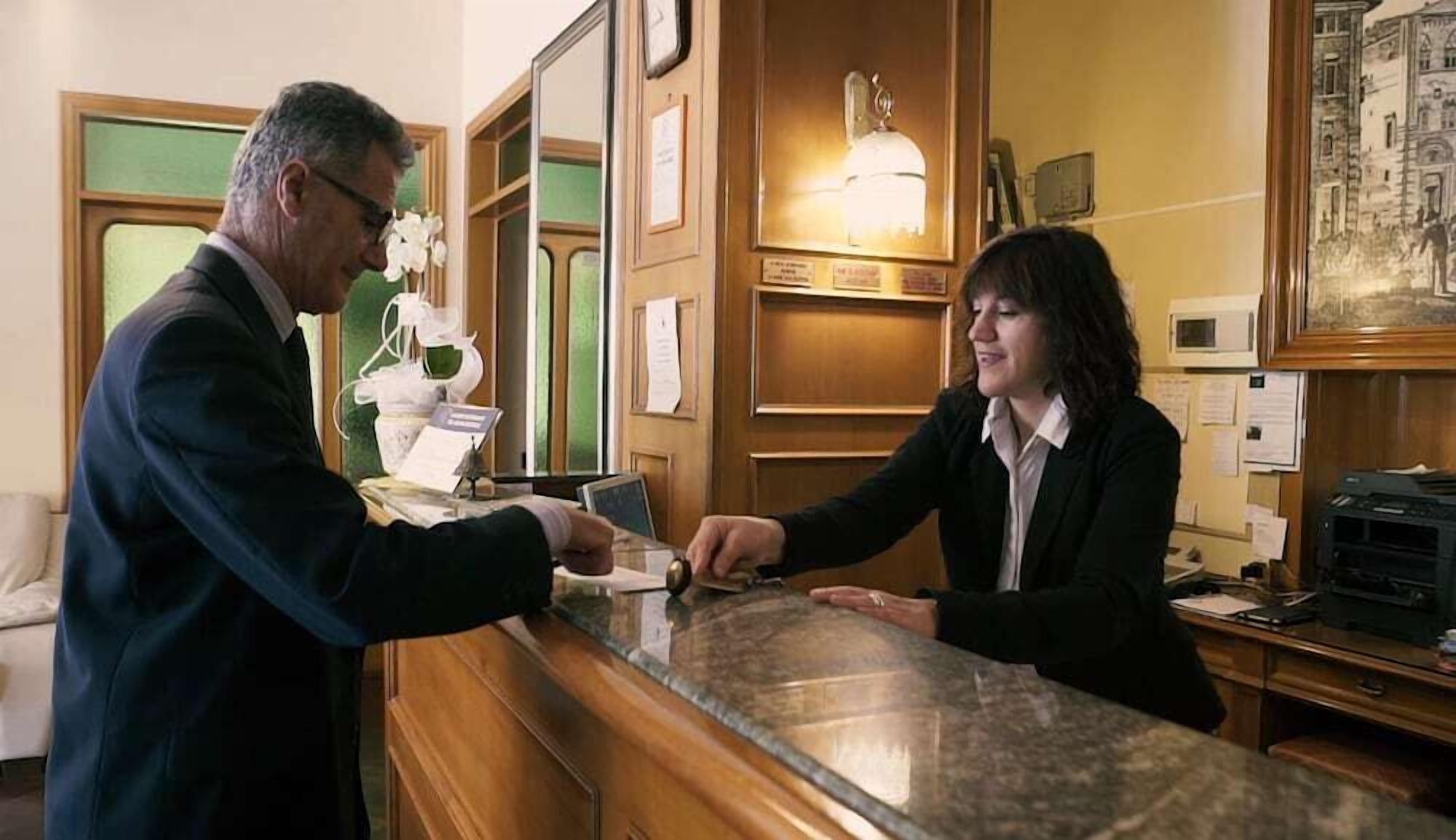 Un'area della reception di un hotel con una scrivania, un orologio e quadri appesi al muro.