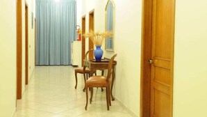 Un pasillo con una mesa de comedor y sillas, un florero azul y un espejo en la pared.