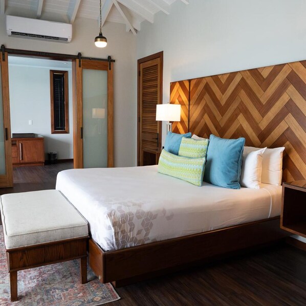 A bedroom with a large bed, wooden headboard, bedside lamps, and a small bedside table.