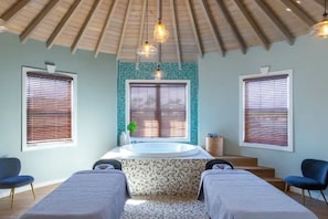 A bathroom with a bathtub, two towels, a sink, and a window with blinds. - Hammock Cove Resort And Spa (Willikies)
