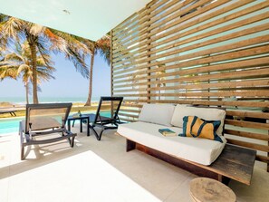A poolside area with a white sofa, two lounge chairs, and a wooden slatted wall. - TUI Blue Tamala (Serrekunda)