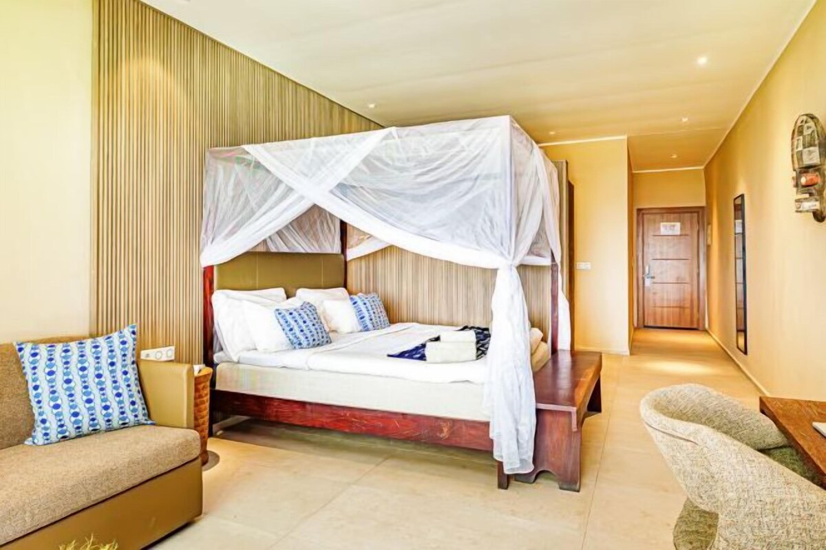 Quarto de hotel com uma cama de dossel, um sofá e uma cadeira.