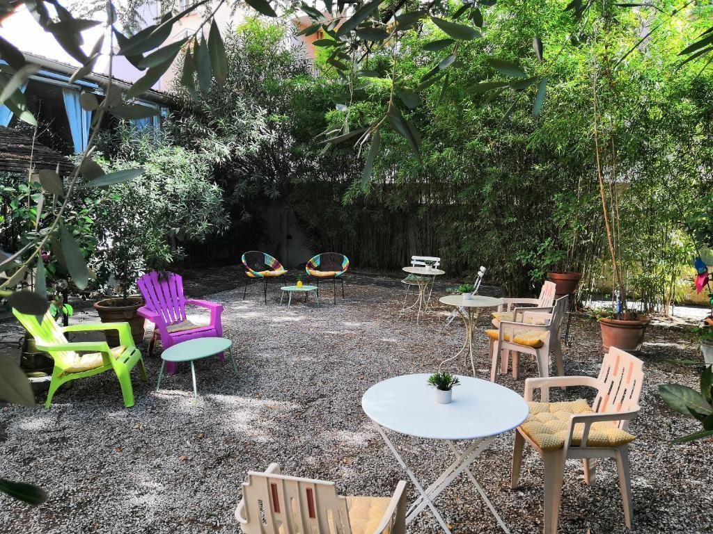 Un patio amueblado con mesas y sillas, rodeado de abundante vegetación y plantas en macetas.