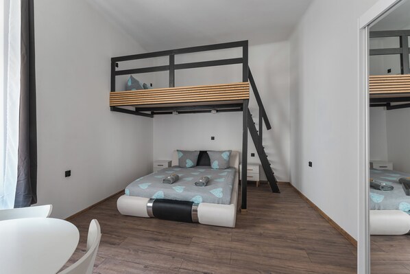 A compact bedroom with a bunk bed, a small bedside table, and a chair. - Queens Apartments (Kraków)