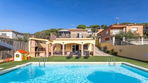 A swimming pool with a sun terrace and lounge chairs, surrounded by a fenced yard and adjacent buildings. - Villa Luz Lloret with Pool (Lloret De Mar)