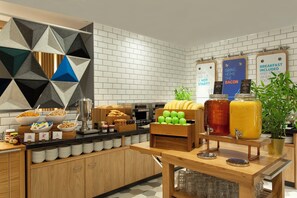 Een ontbijtbuffet met diverse etenswaren, een koffieapparaat en sapautomaten.