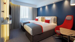 A hotel room with two beds, a red chair, a small table, and a TV. - Holiday Inn Express Barrow In Furness (Barrow-in-Furness)