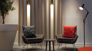 A modern room with two armchairs, a small table, a floor lamp, and a large potted plant. - Holiday Inn Express Barrow In Furness (Barrow-in-Furness)