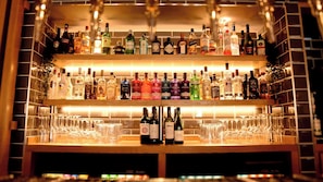 Un bar con múltiples estantes llenos de botellas de licores y vasos.