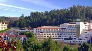 A hotel with multiple floors, a central courtyard, and a view of a forested area. - Monte Rio (Sao Pedro do Sul)