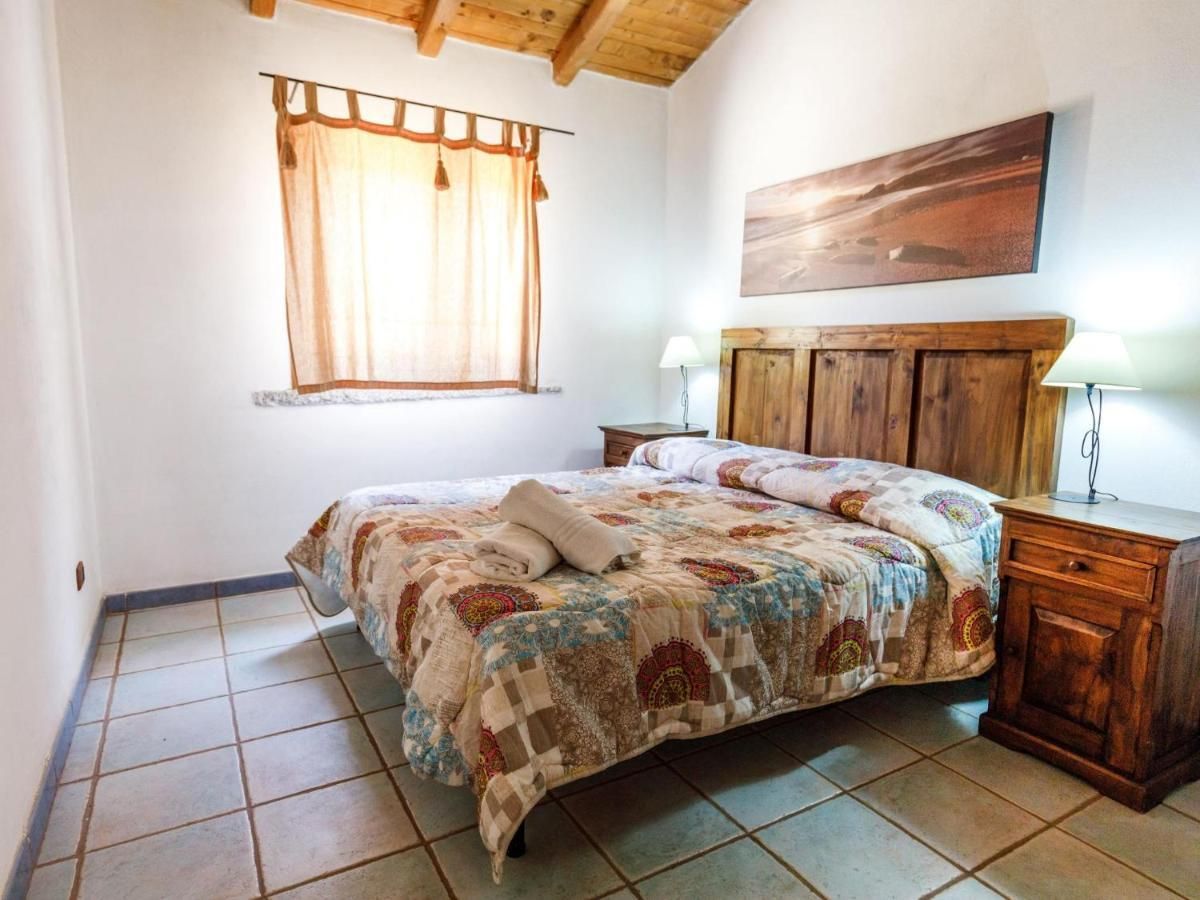 Una camera da letto con un letto, un poggiatesta in legno, un comodino e una finestra con tende.