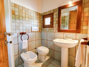 A bathroom with a toilet, bidet, sink, and a mirror above the sink. - Stazzi di Gallura Mare dei Ginepri (Badesi)