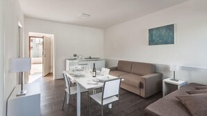 A modern living room with a dining area, a sofa, and a kitchen in the background. - The Florence Hills Resort Spa (Pelago)