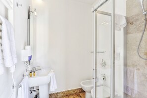A modern bathroom with a glass shower enclosure, a white sink, and a bidet. - The Florence Hills Resort Spa (Pelago)