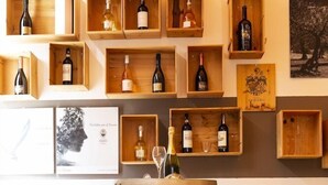 A wine cellar with wooden shelves displaying various wine bottles, a large wooden barrel, and two stools. - The Florence Hills Resort Spa (Pelago)