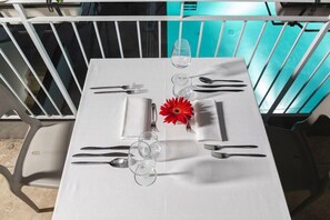 A table set for two with white tablecloth, clear glasses, cutlery, and a red flower. - The Florence Hills Resort Spa (Pelago)