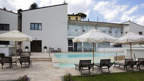 A modern building with a swimming pool, outdoor seating, and a well-maintained garden. - The Florence Hills Resort Spa (Pelago)