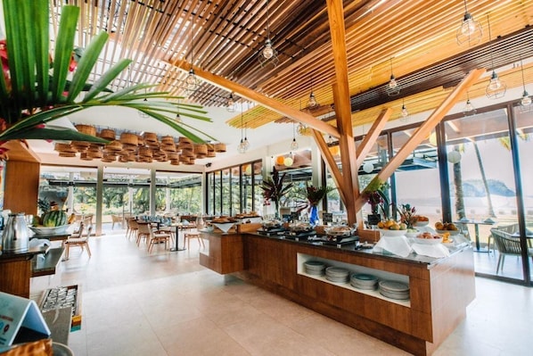 A modern restaurant with a wooden ceiling, large windows, and a buffet counter.