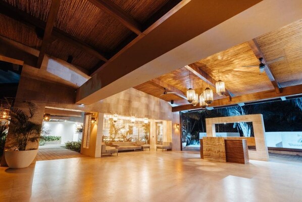 A spacious lobby with a high ceiling, wooden beams, and modern lighting fixtures.