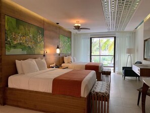 Ein Hotelzimmer mit zwei Betten, einem Schreibtisch, einem Stuhl und einem großen Fenster.