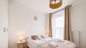 Une chambre à coucher bien rangée, avec un lit, une table de chevet et une fenêtre avec des rideaux.